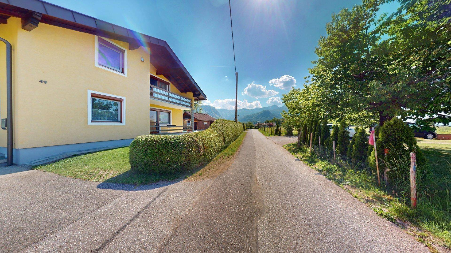 Zufahrtsstraße zum Anwesen mit dem Haupthaus im Hintergrund und Bergblick.