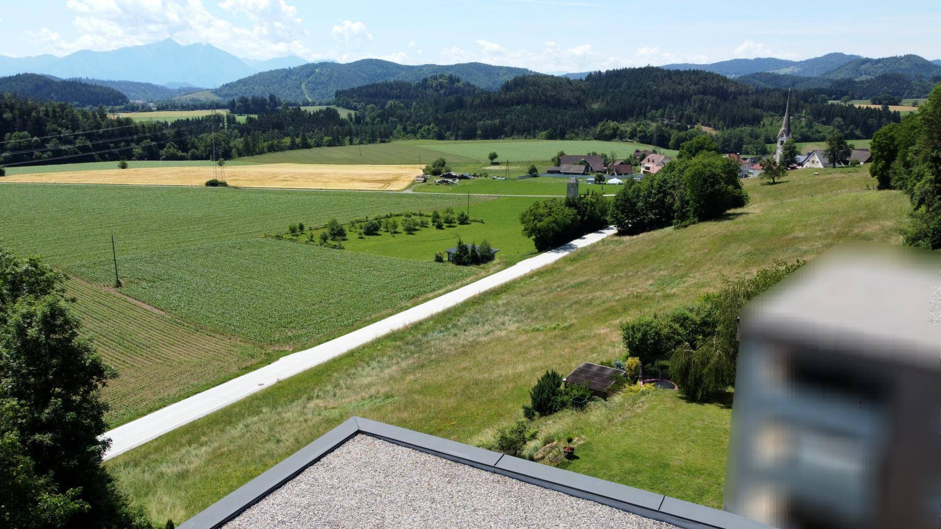 Panoramablick über die ländliche Umgebung mit Feldern, Wäldern und einem Dorf in der Ferne.