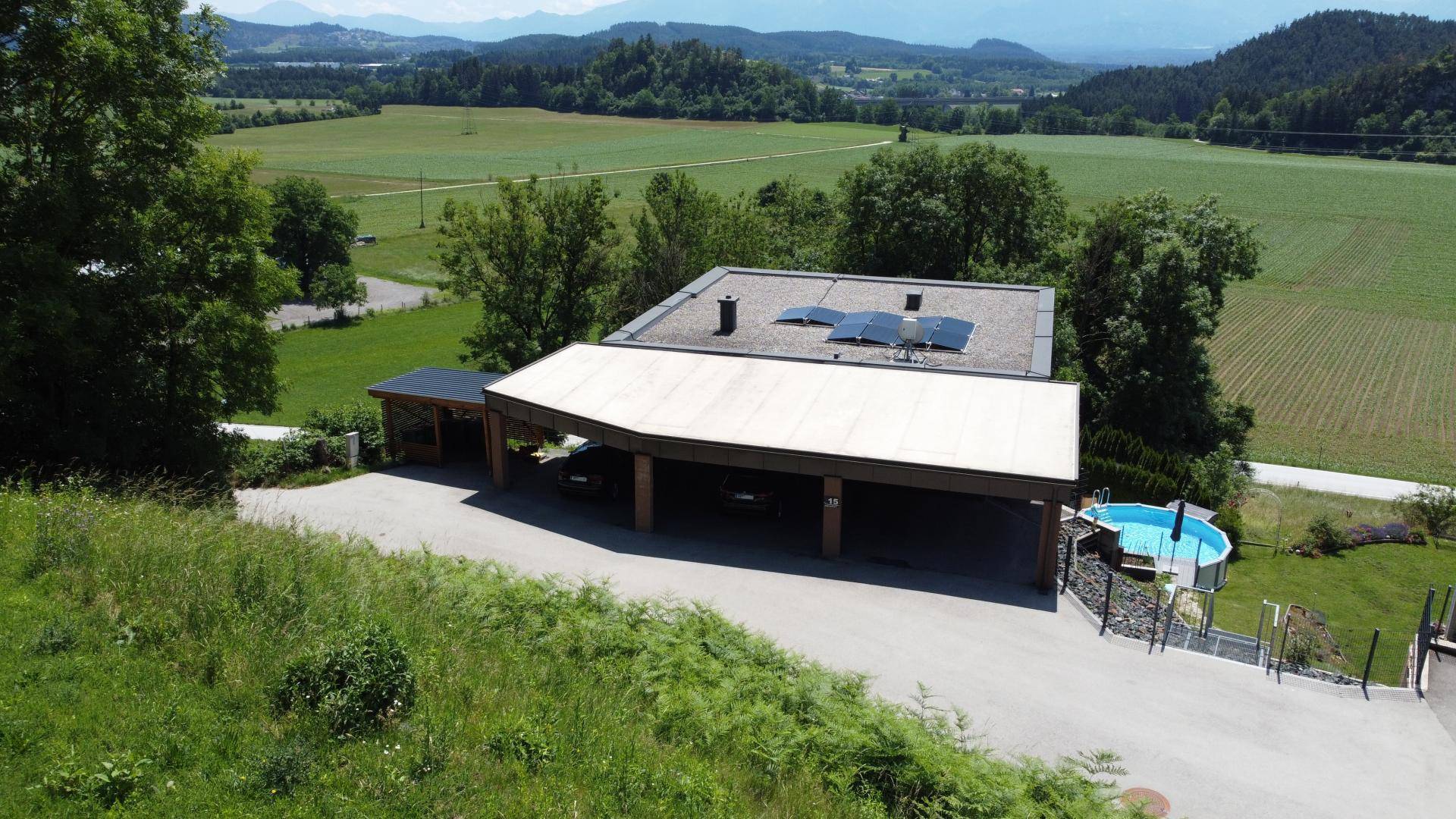 Luftaufnahme des Anwesens mit Carport, Pool und weitreichender Landschaft.