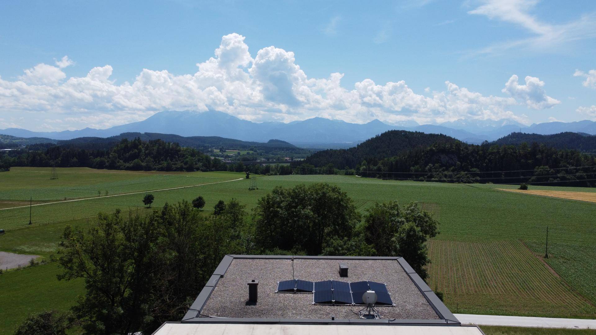 Weitläufiger Blick über grüne Felder und Berge vom Dach des Gebäudes.