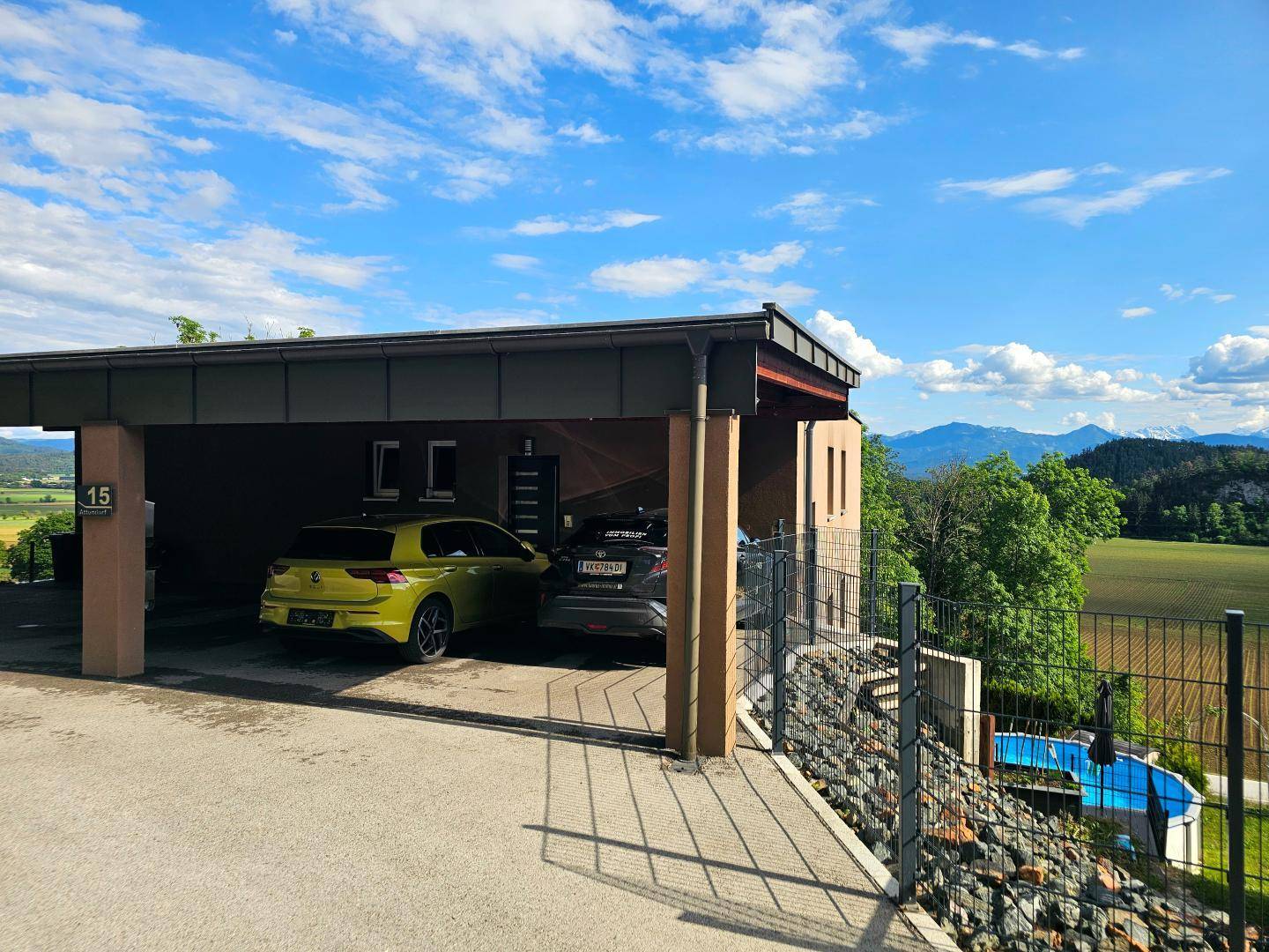 Modernes Haus mit Carport und weitem Blick auf die umliegende Landschaft und Berge.