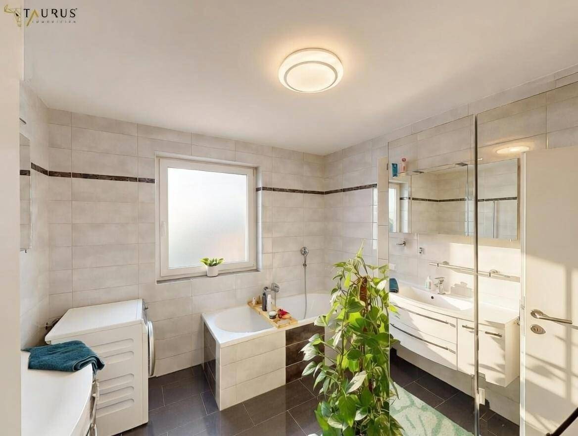 Modernes Badezimmer mit Badewanne, Dusche, Waschbecken und Fenster.