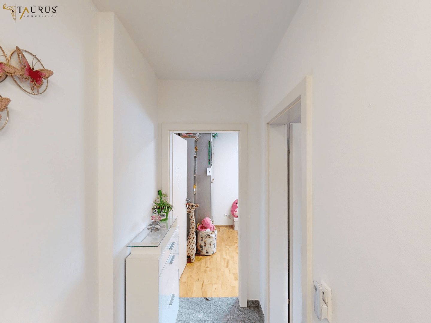 Heller Flur mit Dekoration und Blick in ein weiteres Zimmer.