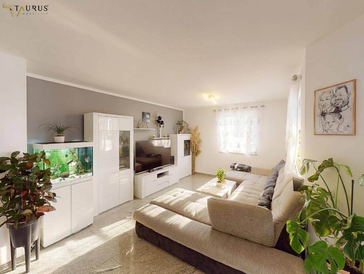 Geräumiges Wohnzimmer mit großem Sofa, Aquarium und Granitboden.