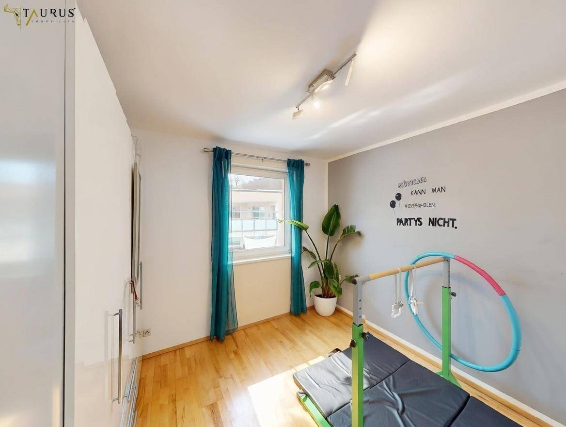 Kinderzimmer oder Gästezimmer mit Holzboden, Fenster und Sportgeräten.