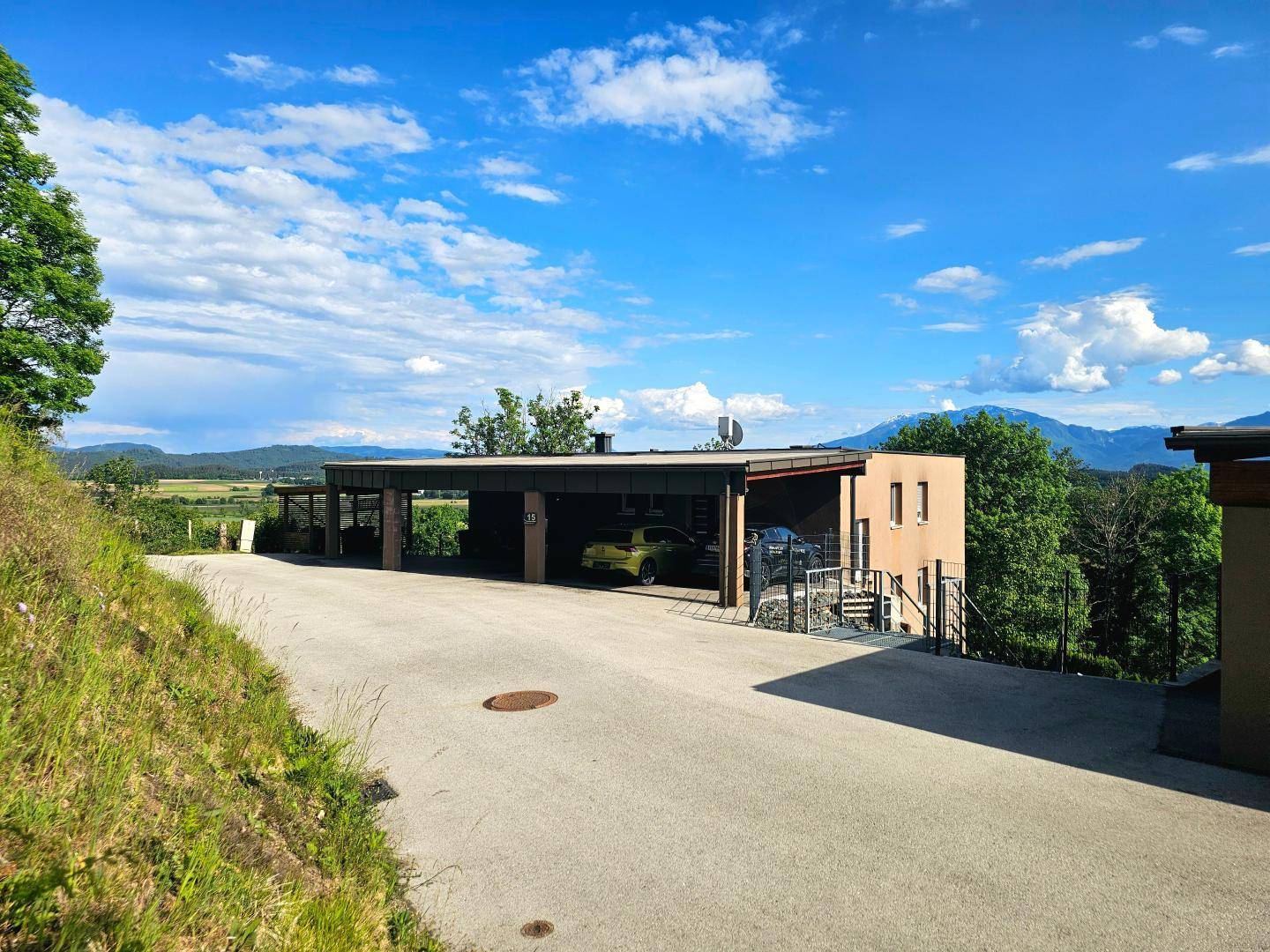 Zufahrt zum Anwesen mit Carport und Blick auf die umliegende Landschaft.