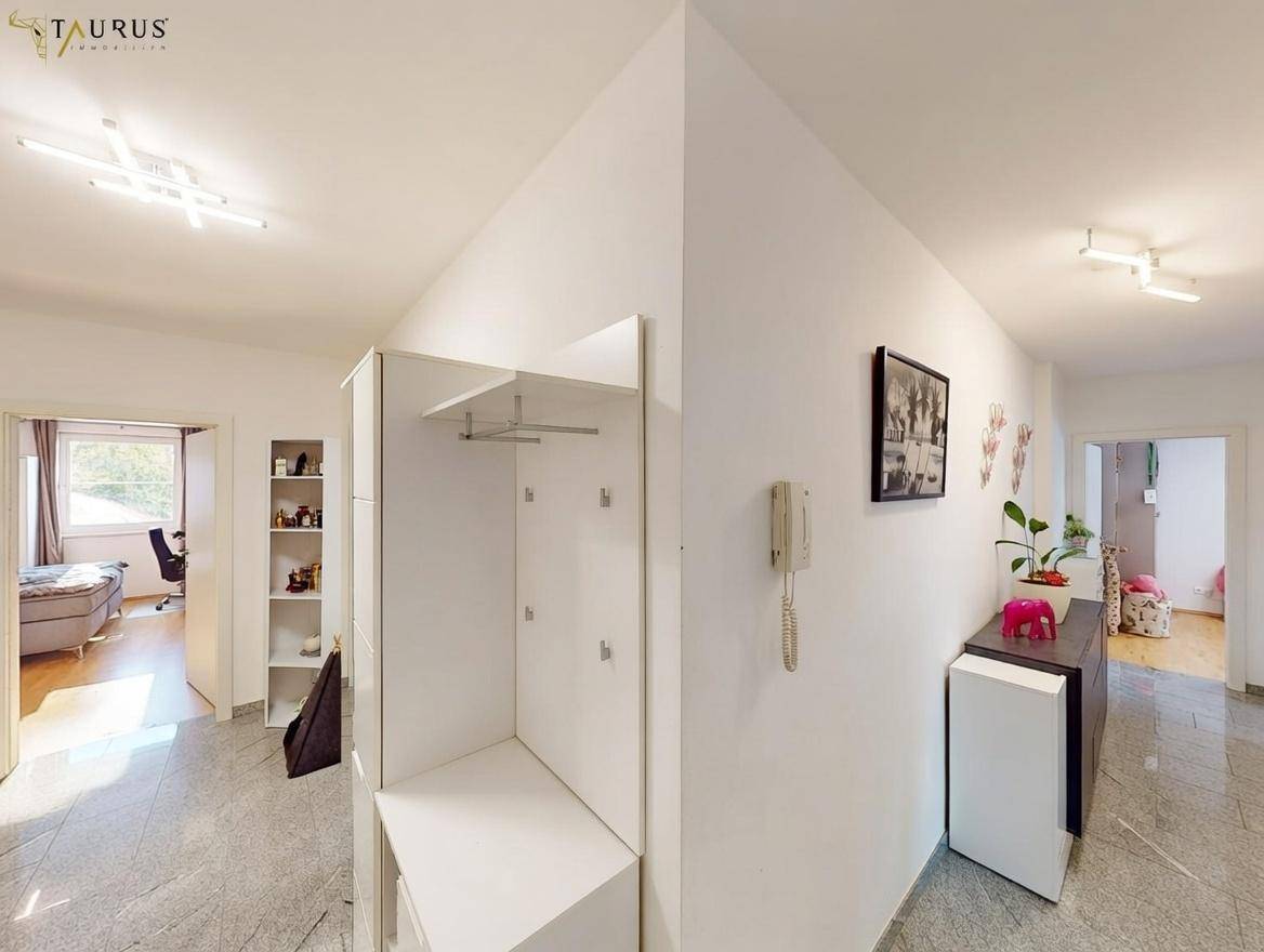 Heller Flur mit Garderobe und Granitboden, der zu weiteren Räumen führt.