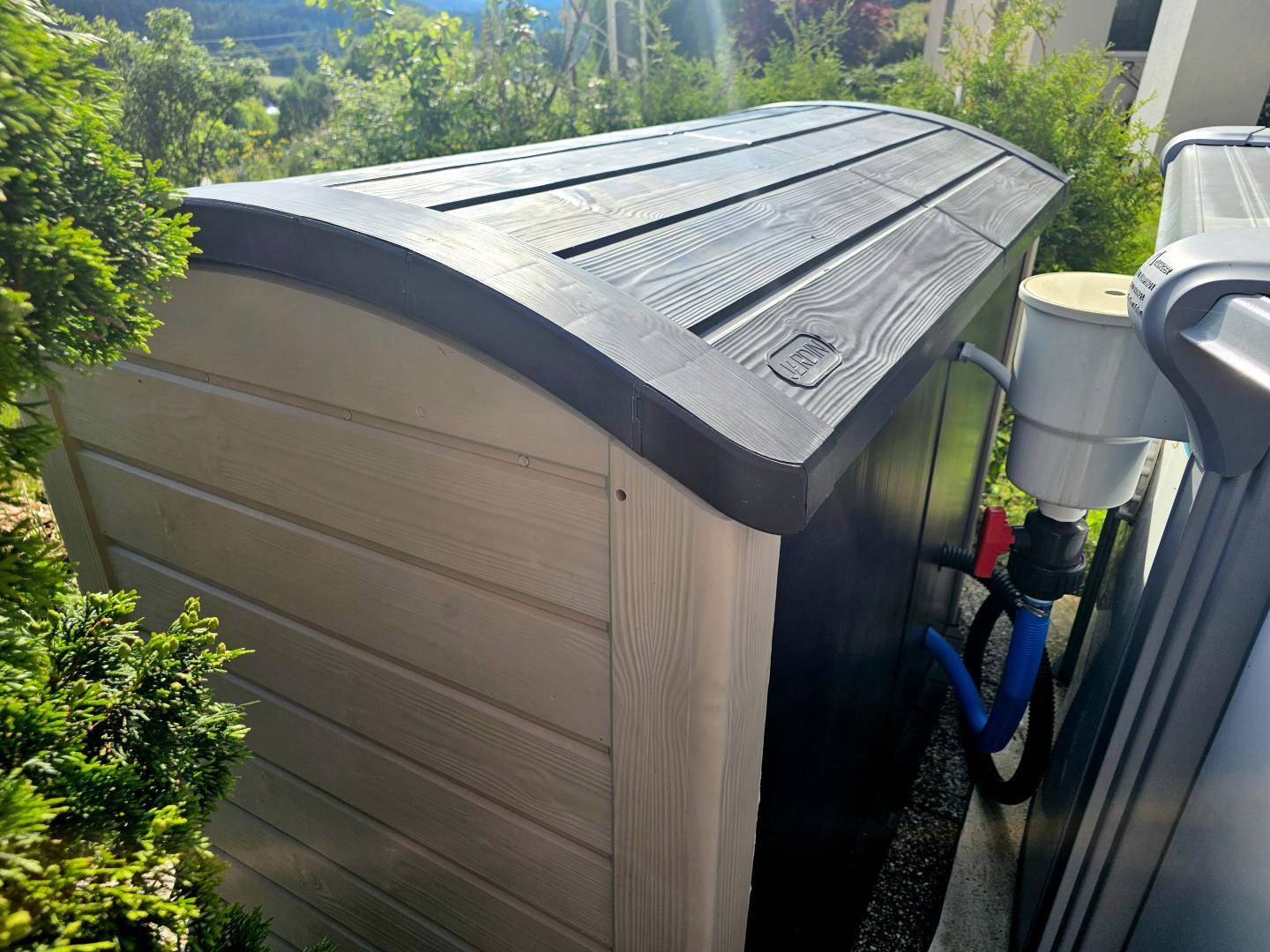 Outdoor-Aufbewahrungsbox in Holzoptik neben der Pooltechnik im Gartenbereich.