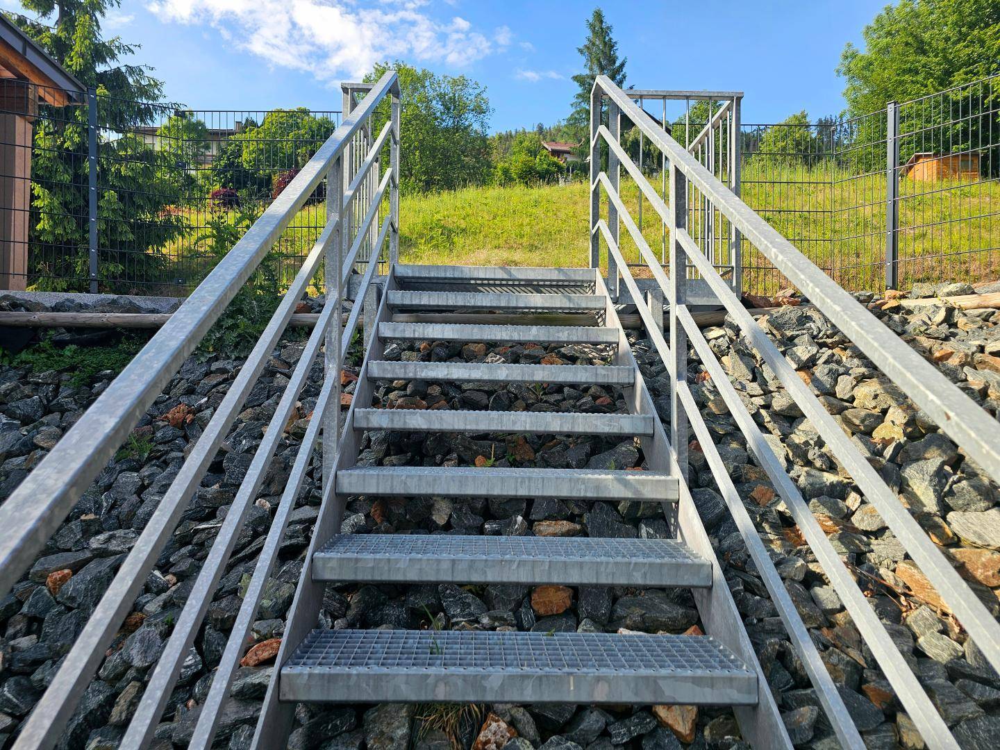 Robuste Metalltreppe im Außenbereich, die zu einem höher gelegenen Teil des Grundstücks führt.