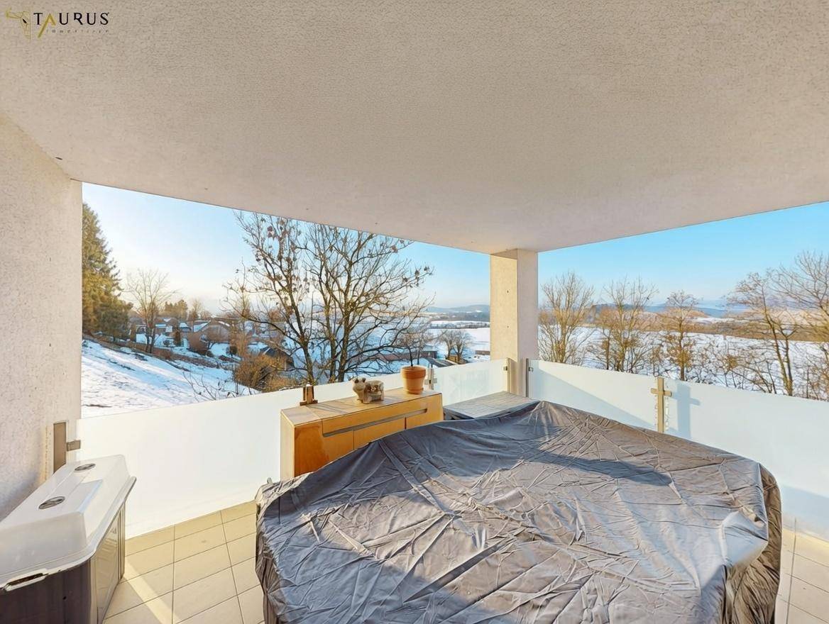 Überdachter Balkon mit weitem Blick über die verschneite Landschaft und Berge.