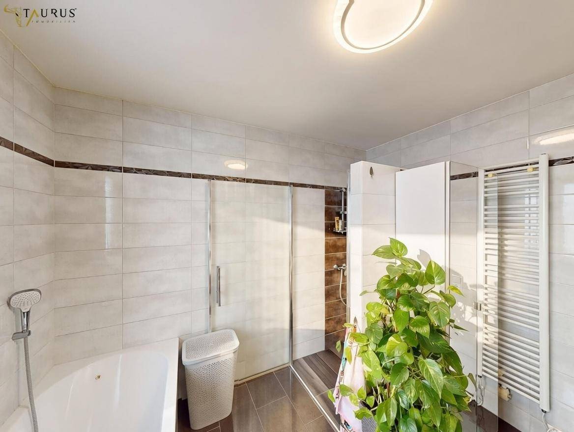 Badezimmer mit Duschkabine, Badewanne und Heizkörper, hell gefliest.