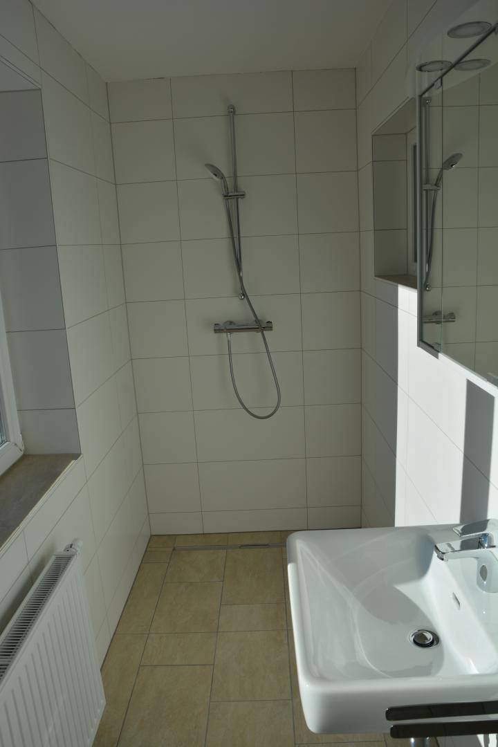Modernes Badezimmer mit Duschbereich, Waschbecken und weißen Fliesen.