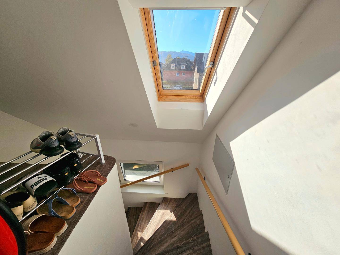Helles Treppenhaus mit Dachfenster, das den oberen Bereich mit Sonnenlicht durchflutet.