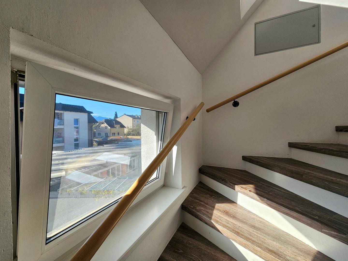 Treppenhaus mit großem Fenster, das viel Tageslicht hereinlässt und einen Ausblick bietet.