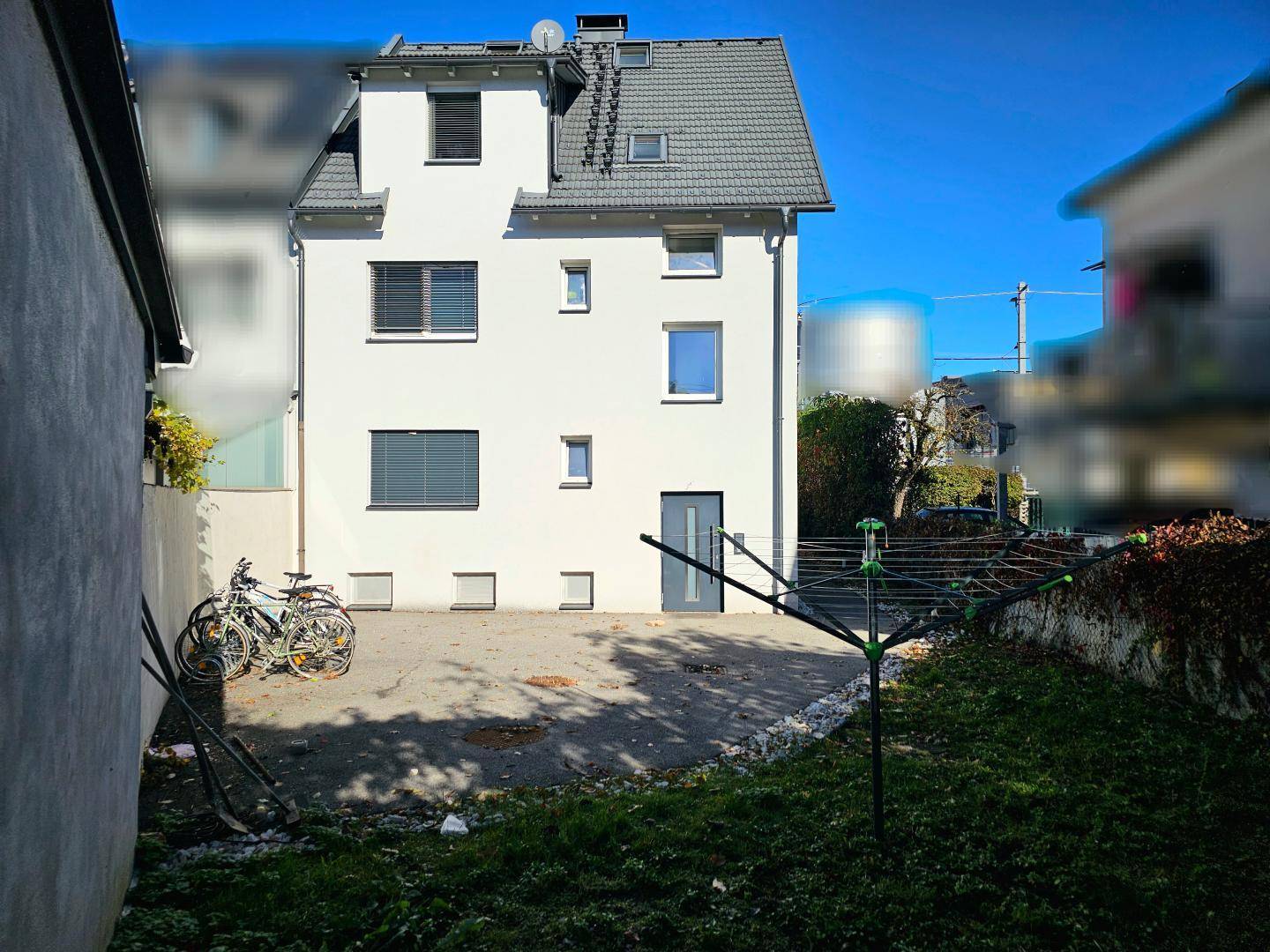 Hinteransicht eines weißen Wohnhauses mit kleinem Gartenbereich und Wäschespinne.