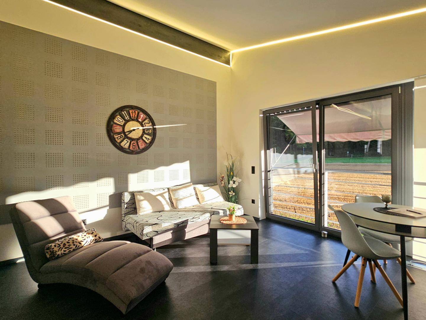Stilvolles Wohnzimmer mit bequemen Möbeln, dekorativer Wandgestaltung und viel Tageslicht.