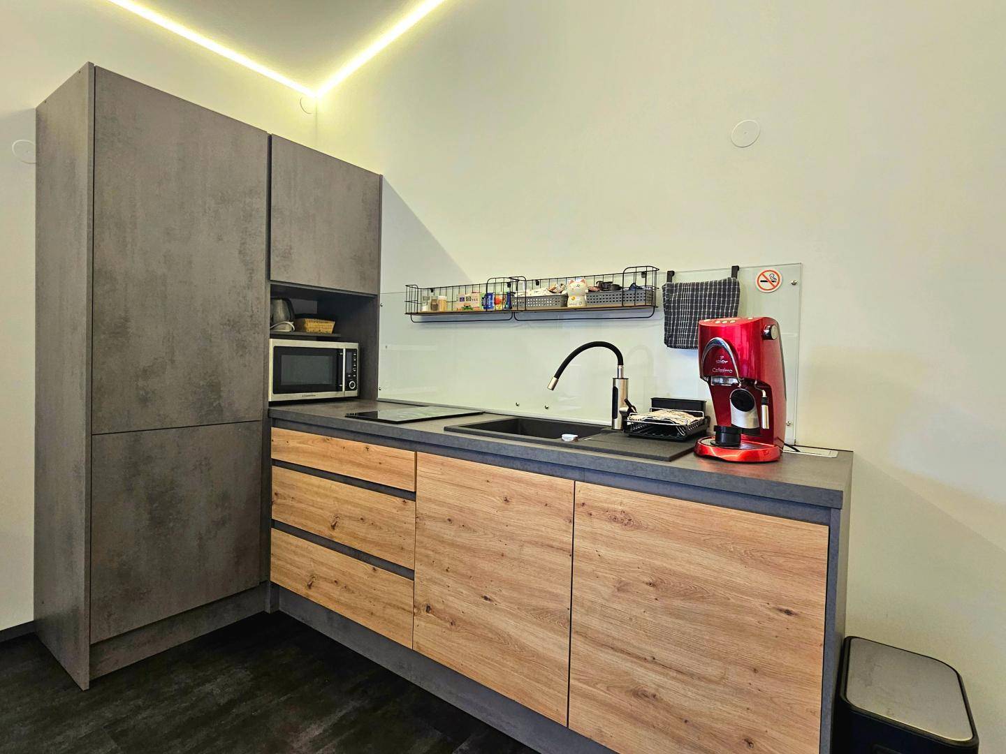 Detailansicht der modernen Küchenzeile mit Holz- und Grautönen sowie integrierter Mikrowelle.