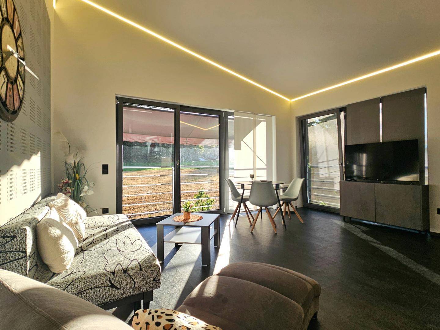 Gemütliches Wohnzimmer mit Sofa, Esstisch und Zugang zu einem Balkon mit Markise.