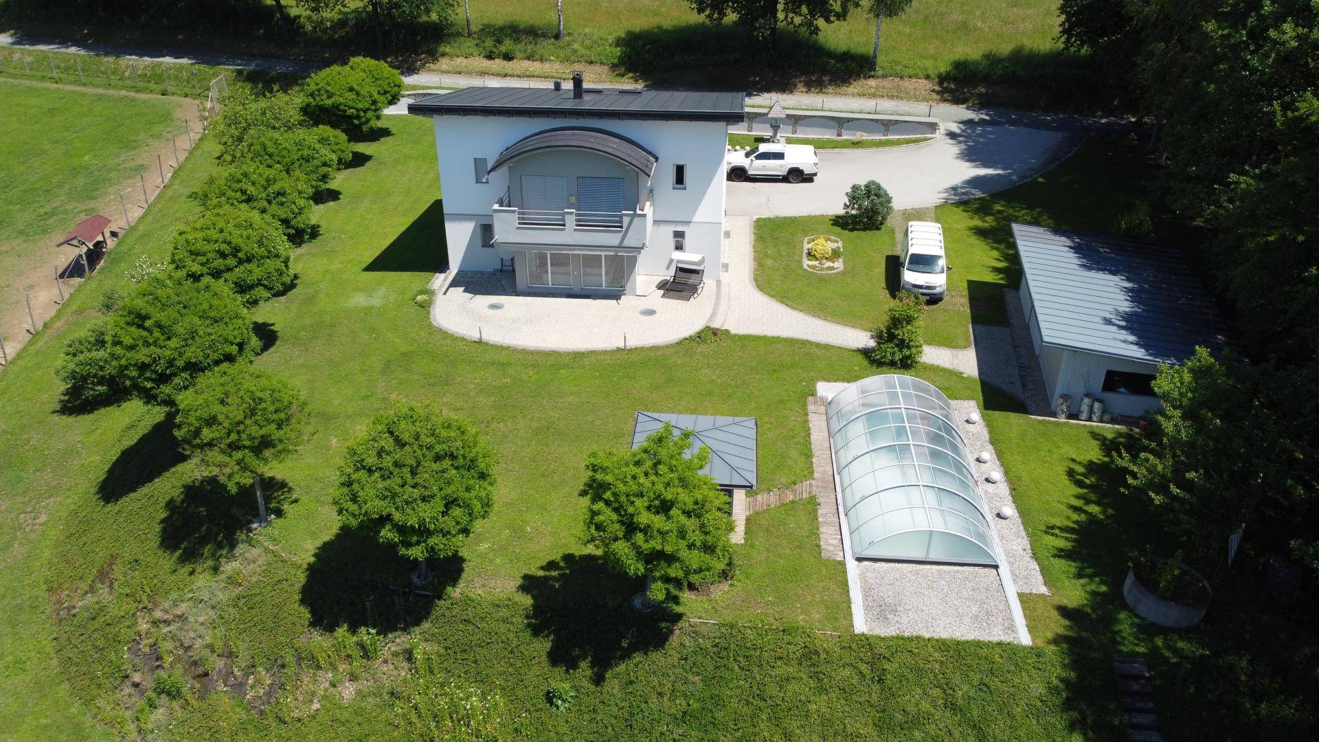 Luftaufnahme des Hauses mit gepflegtem Garten, überdachtem Poolbereich und kleinem Balkon.