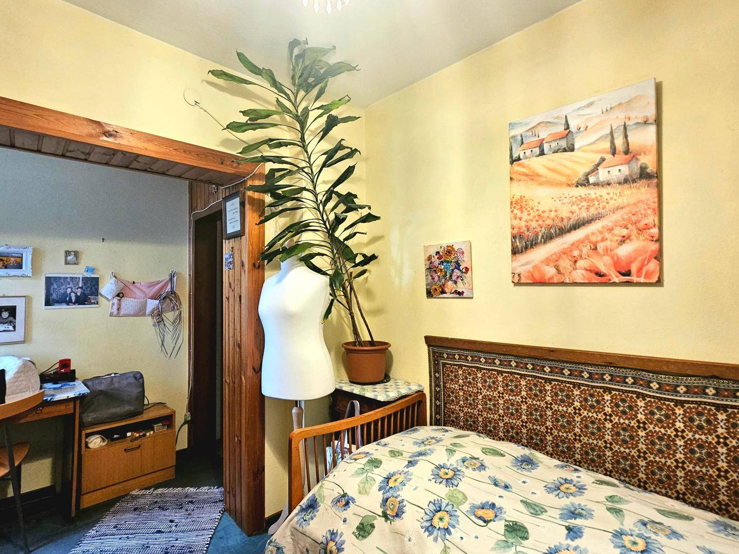 Schlafzimmer mit gelben Wänden und Blick durch eine offene Tür in einen angrenzenden Raum.