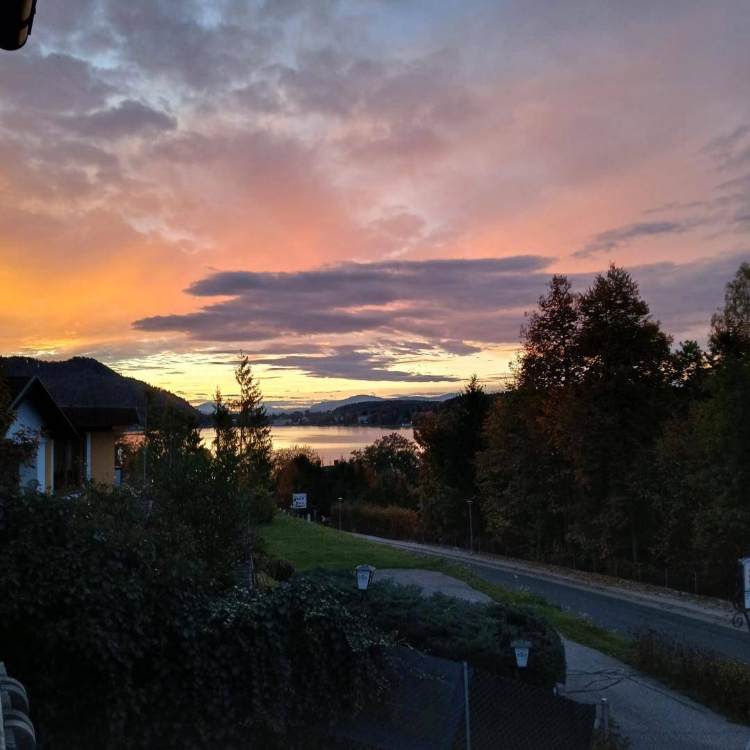 Spektakulärer Sonnenuntergang über dem See, gesehen von einem Balkon mit weitem Blick.