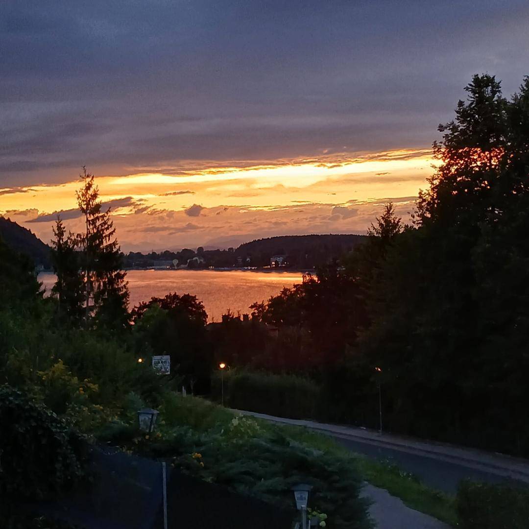 Dunkler Abendhimmel über dem See mit leuchtenden Farben des Sonnenuntergangs am Horizont.