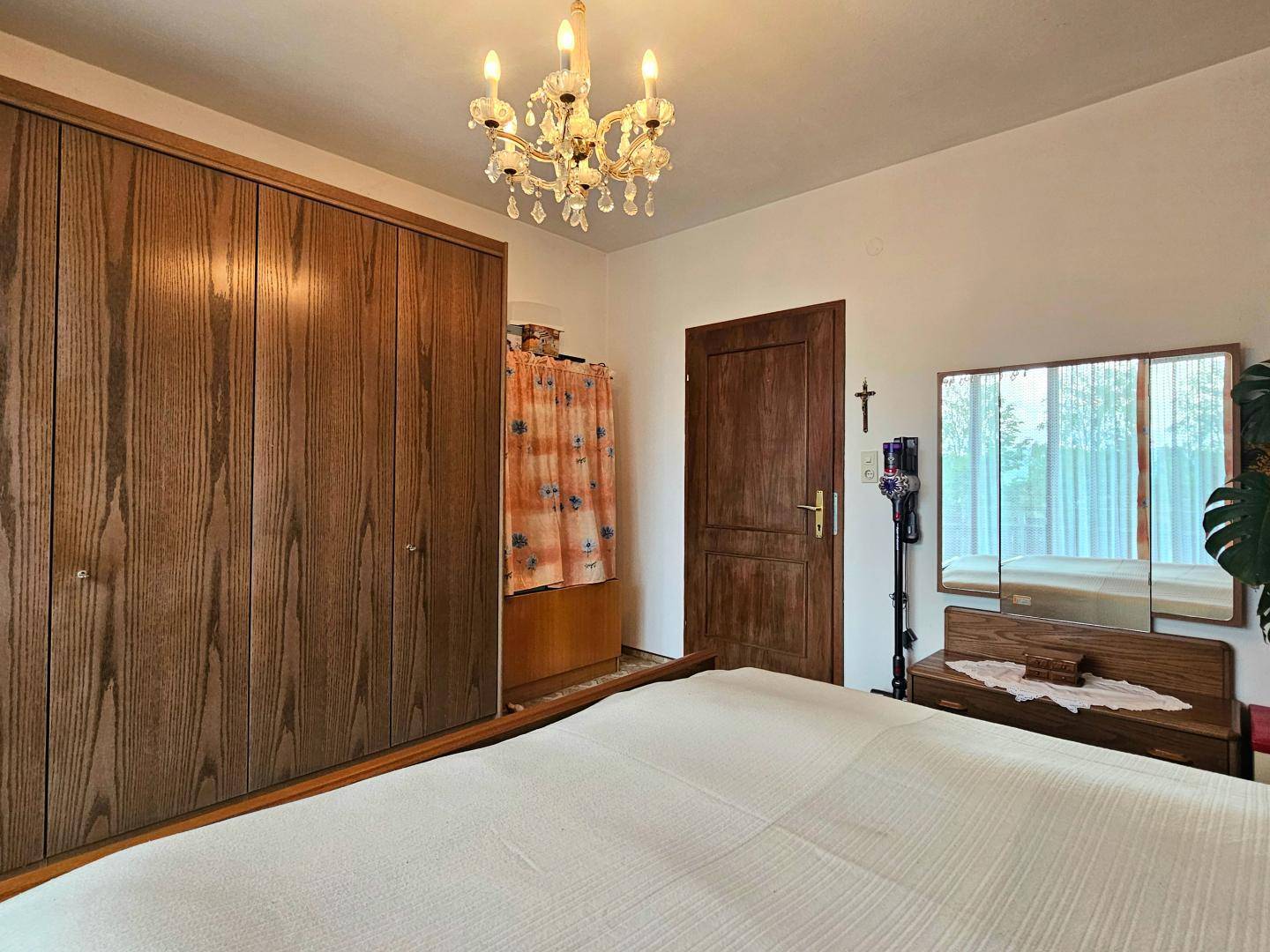 Geräumiges Schlafzimmer mit großem Holzschrank, Doppelbett und klassischem Kronleuchter.
