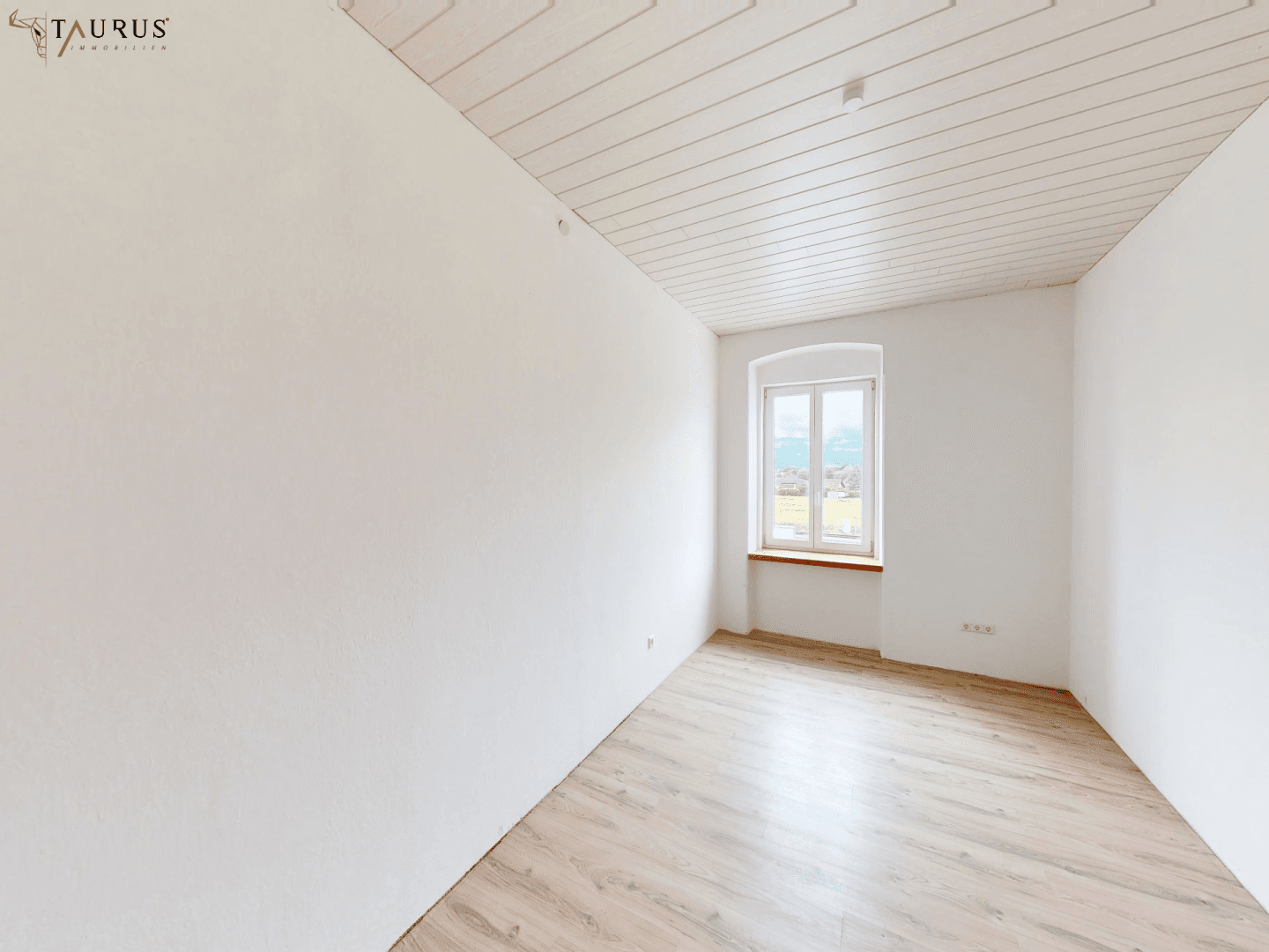 Renoviertes Zimmer mit Laminatboden und weiß gestrichenen Wänden, ideal als Schlafzimmer.