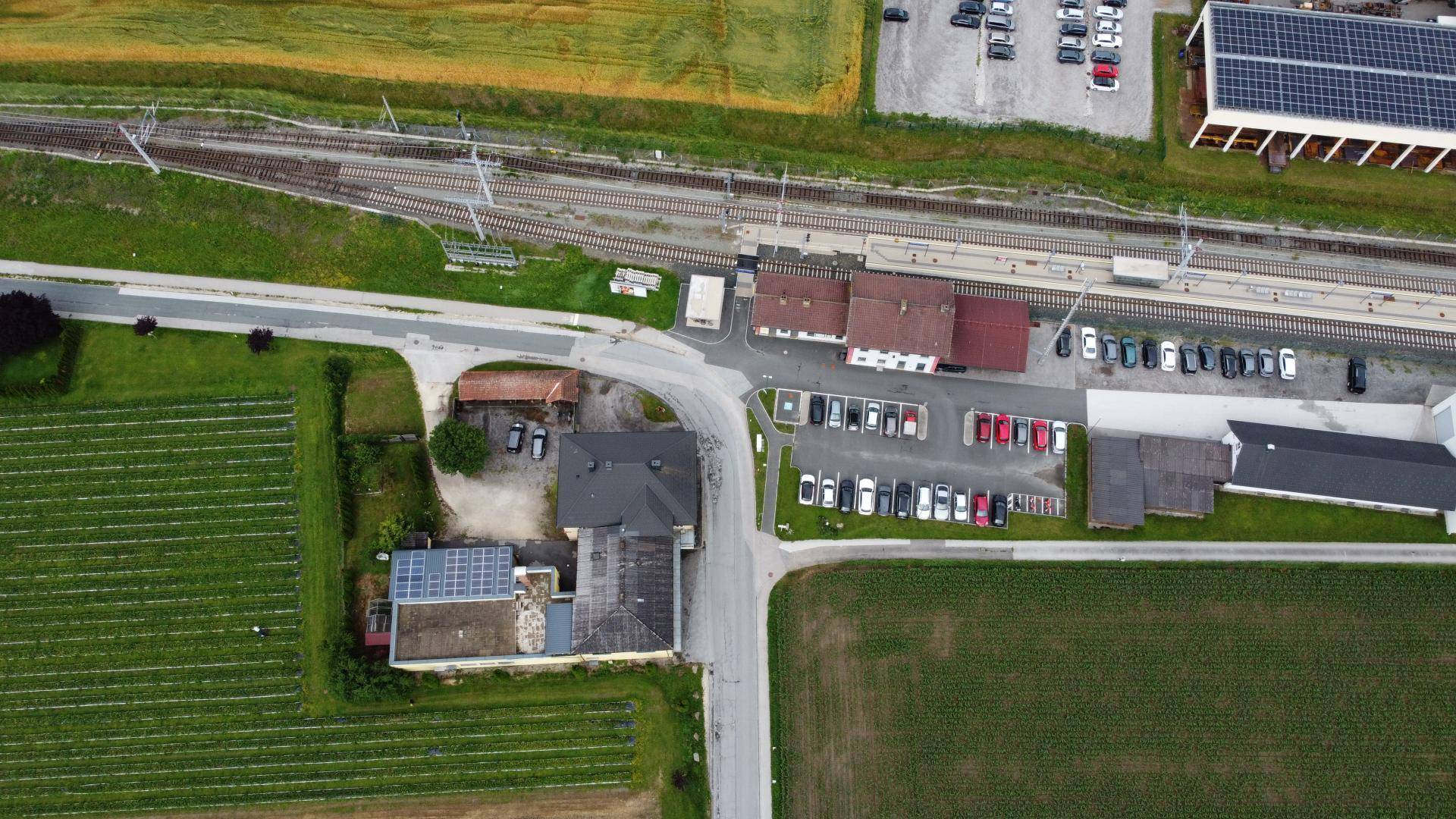 Vogelperspektive des Anwesens mit Bahngleisen, Parkplätzen und landwirtschaftlichen Flächen.