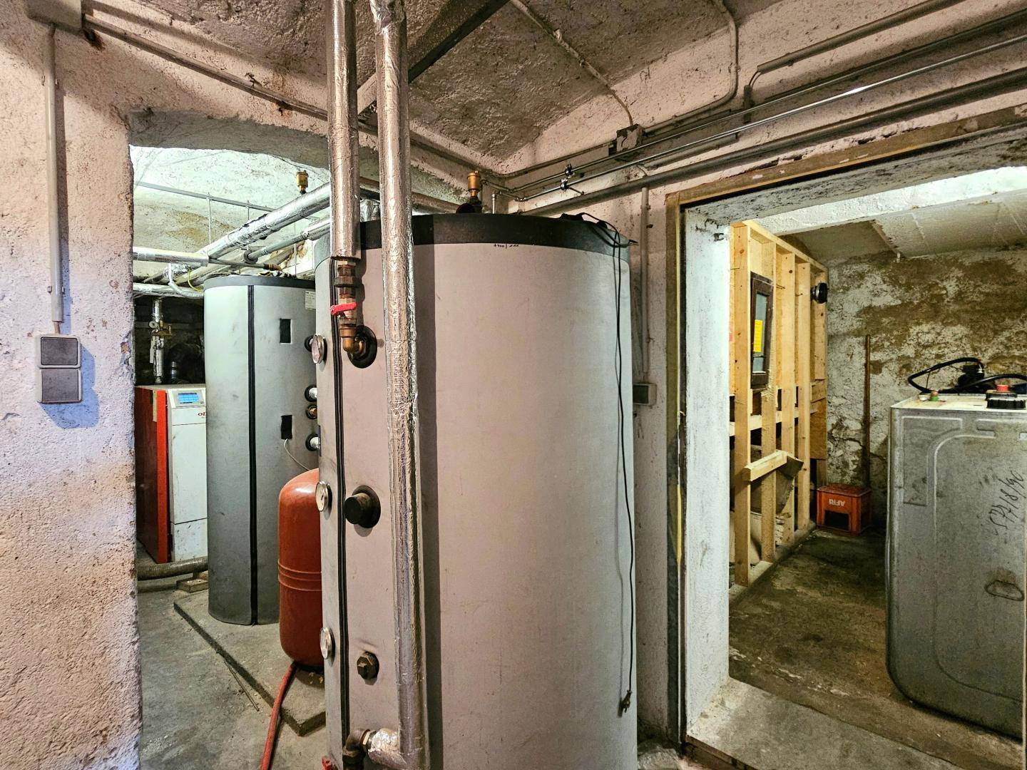 Heizungsraum im Keller mit großen Warmwasserspeichern und Rohrleitungen.