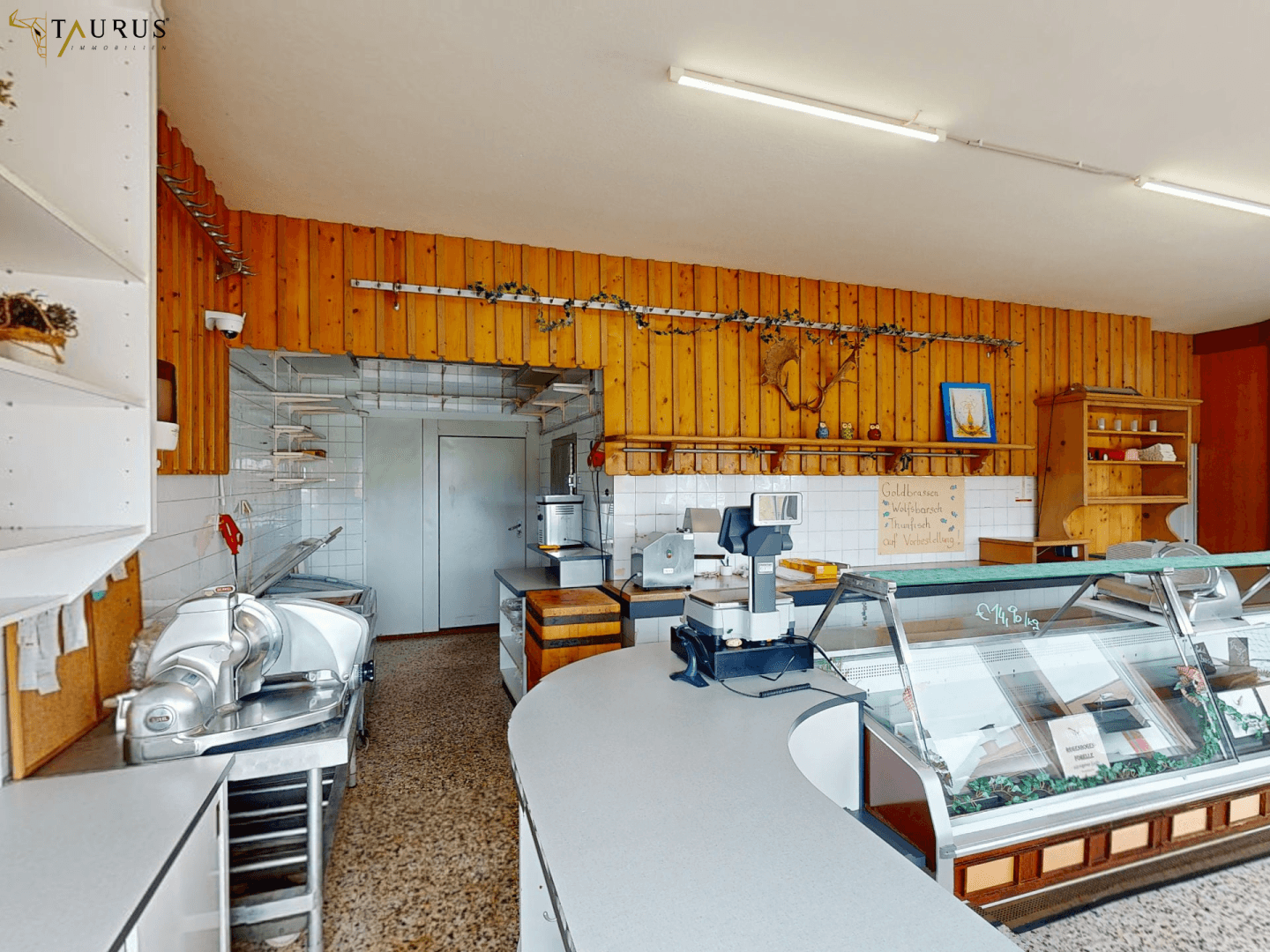 Arbeitsbereich mit Theke, Schneidemaschinen und gefliesten Wänden, ideal für Lebensmittelverarbeitung.