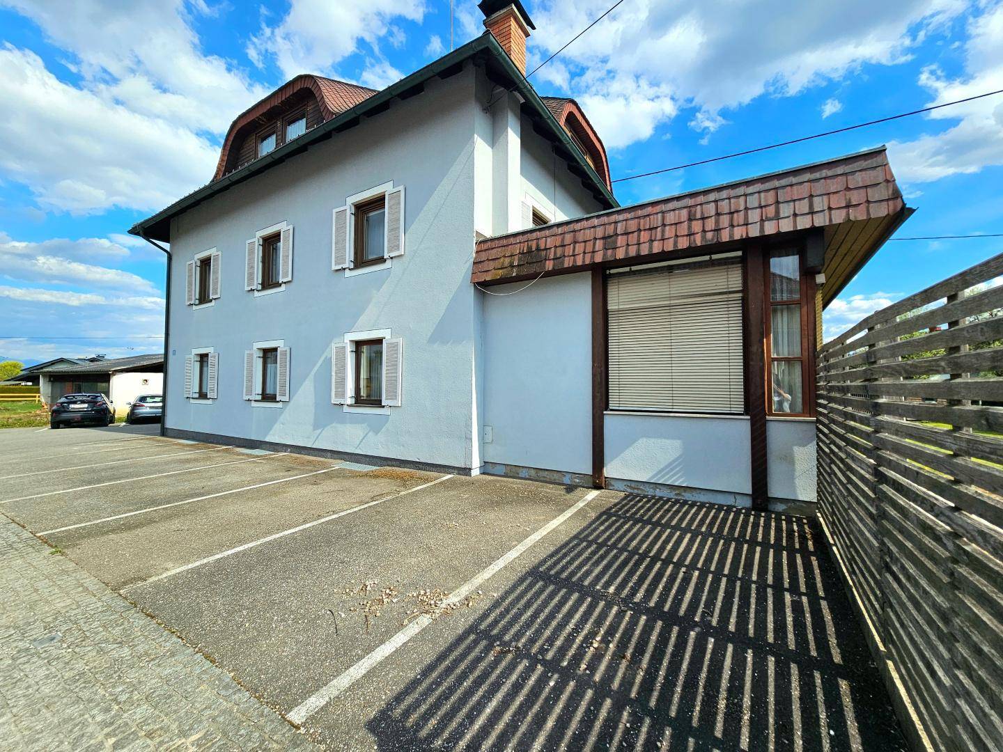 Seitenansicht des Hauses mit mehreren Außenparkplätzen und einem Holzzaun.