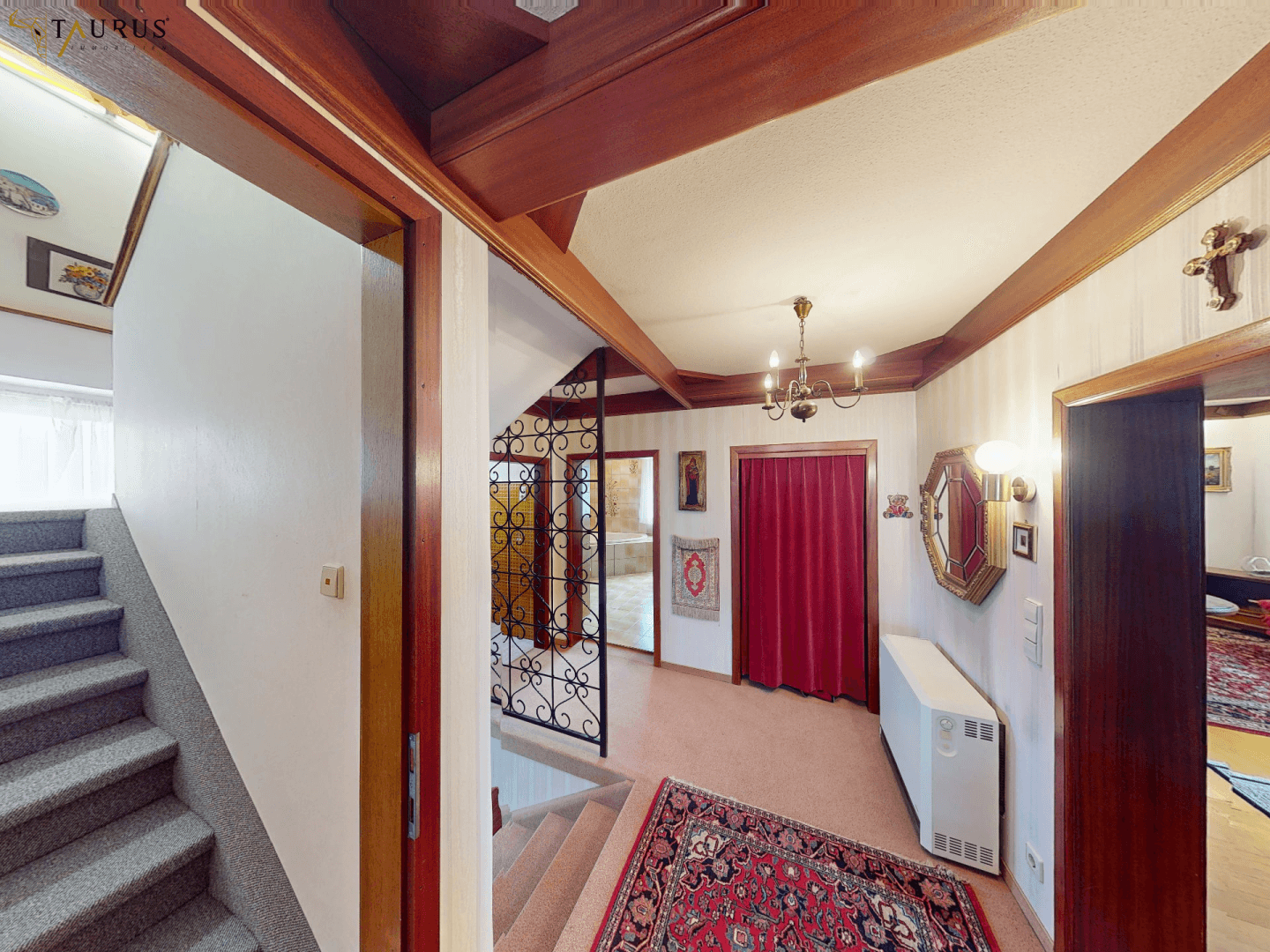 Traditioneller Flur mit Holzdecken, Teppichboden und einer Treppe, die in die oberen Stockwerke führt.