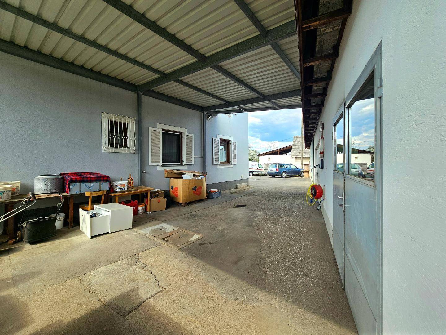 Überdachter Außenbereich neben dem Gebäude, ideal als Carport oder Lagerfläche.
