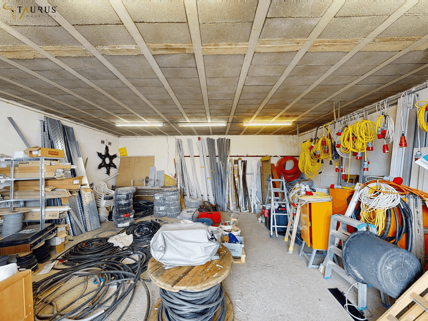 Geräumiger Werkstatt- oder Lagerraum mit vielen Kabeln, Werkzeugen und Baumaterialien.