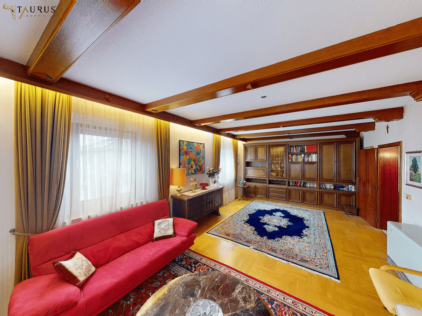 Wohnzimmer mit großem Einbauschrank, Holzbalkendecke und Parkettboden.