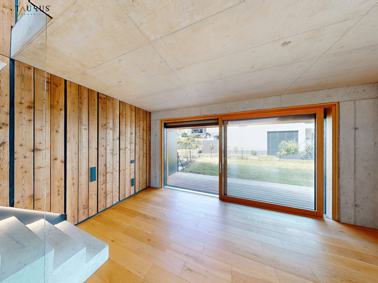 Heller Raum mit Holzboden und großer Schiebetür, die den Zugang zum Außenbereich ermöglicht.
