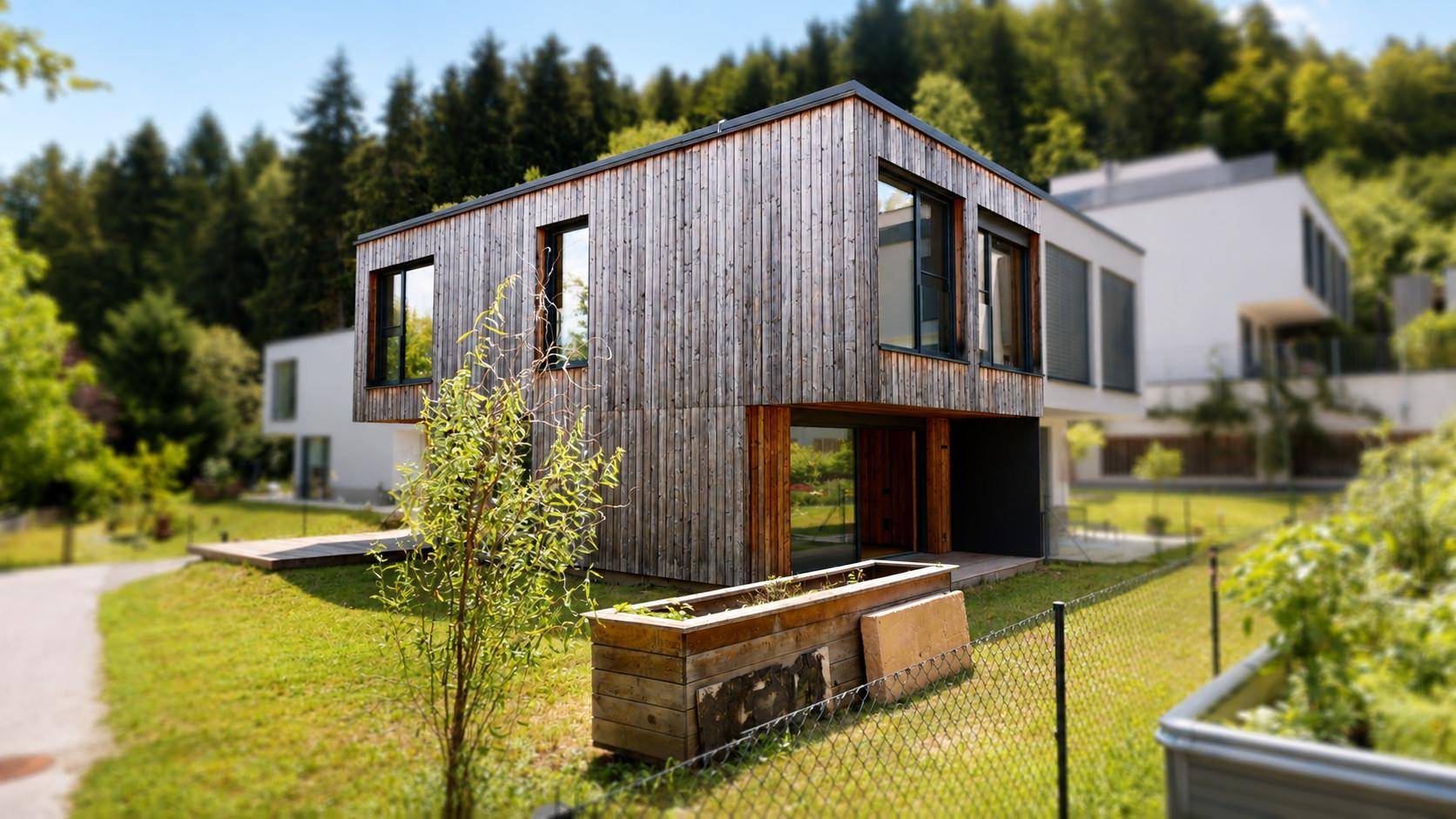 Modernes Einfamilienhaus mit Holzfassade und Gartenbereich in grüner Umgebung.