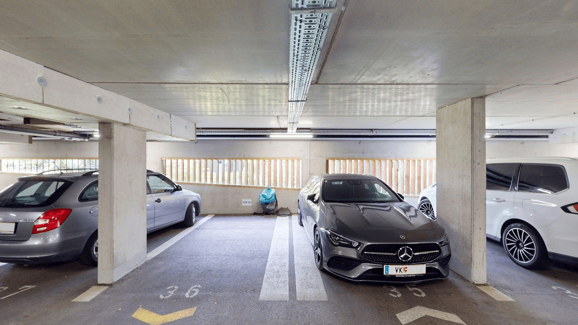 Tiefgarage mit mehreren Stellplätzen und Beleuchtung unter der Betondecke.