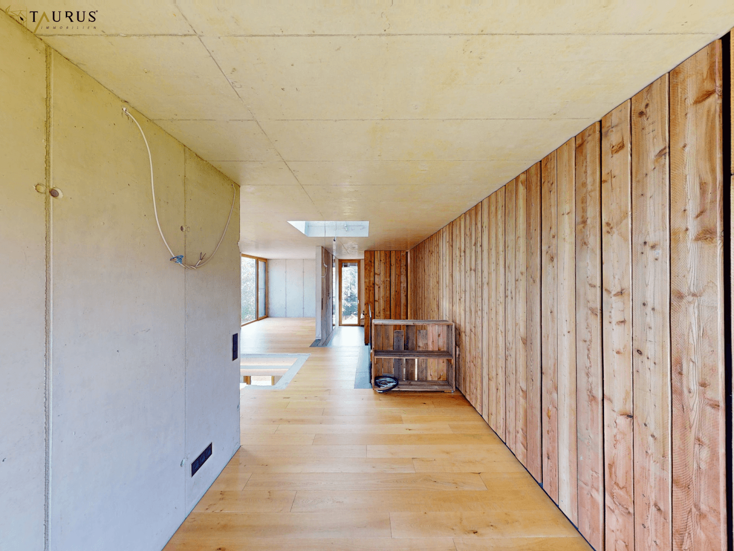 Langer Flur im Obergeschoss mit Holzboden, Holzverkleidung und Oberlicht.
