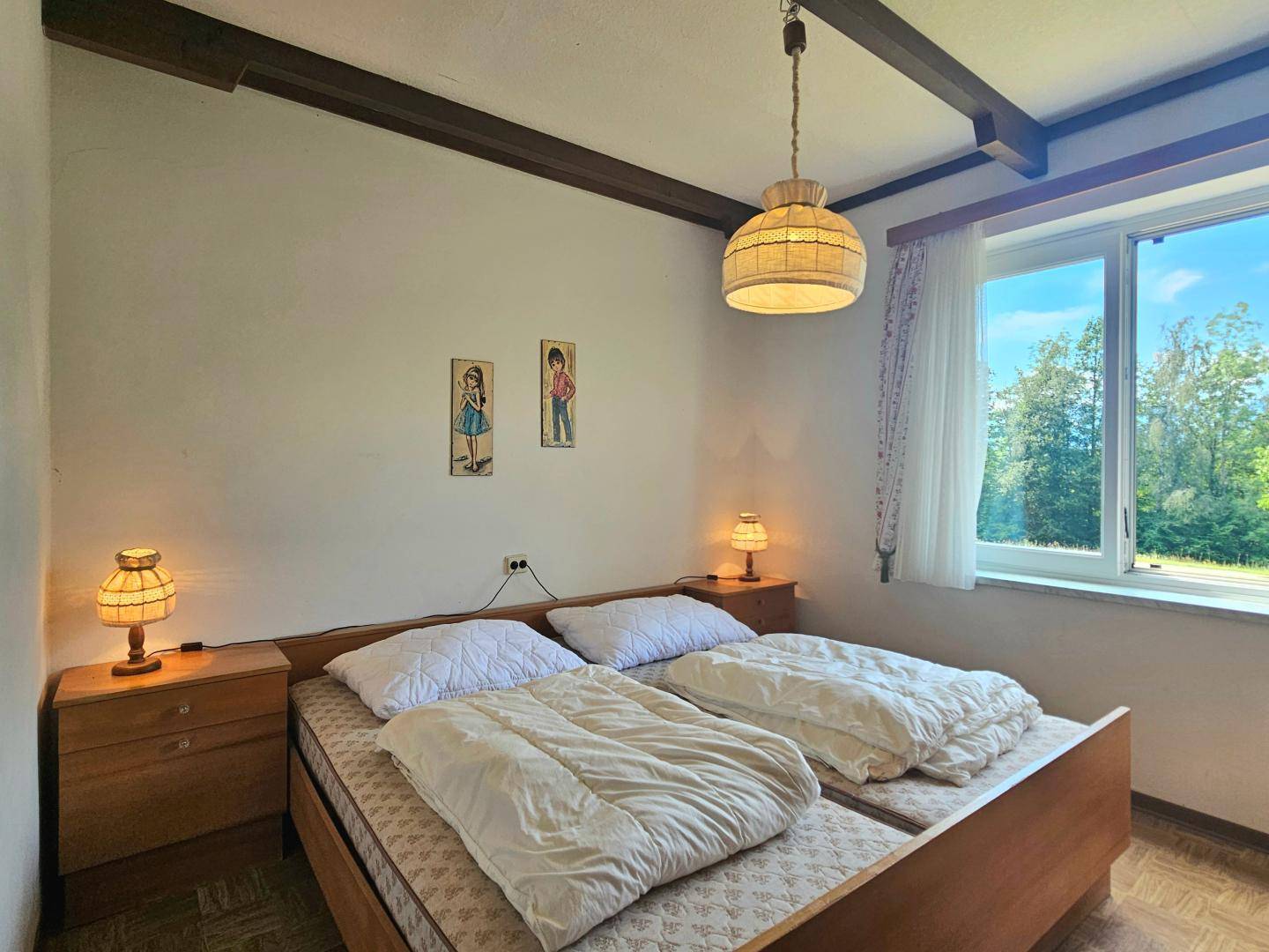 Gemütliches Schlafzimmer mit zwei Einzelbetten, Holzmöbeln und Blick ins Grüne.