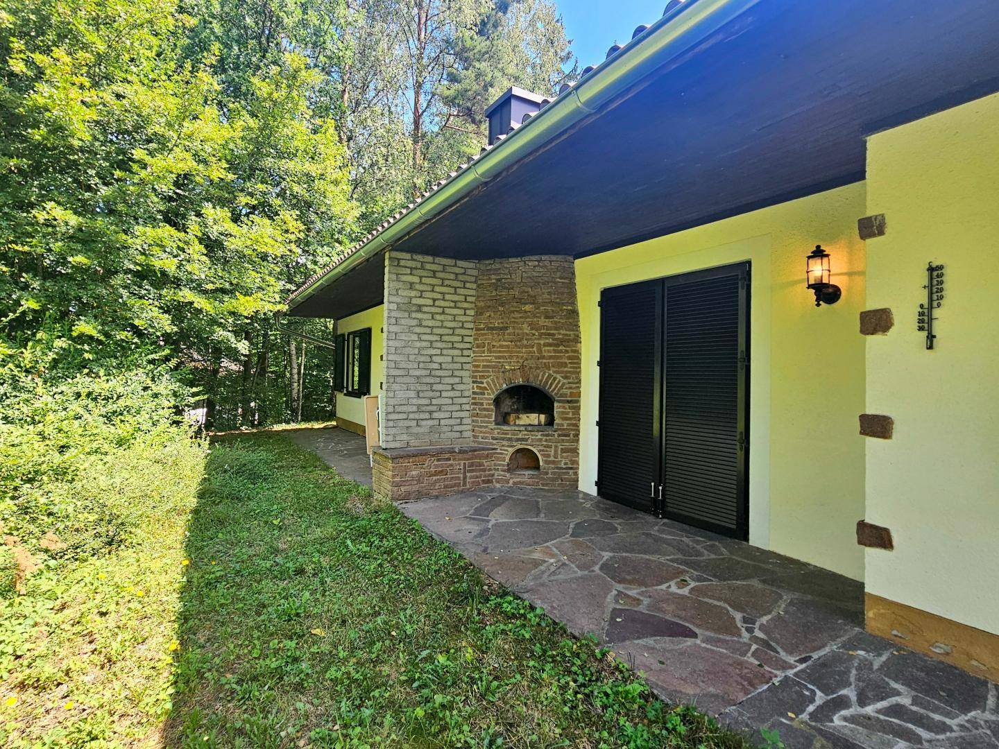 Terrasse mit rustikalem Steinboden und Außenkamin, ideal für gesellige Abende im Freien.