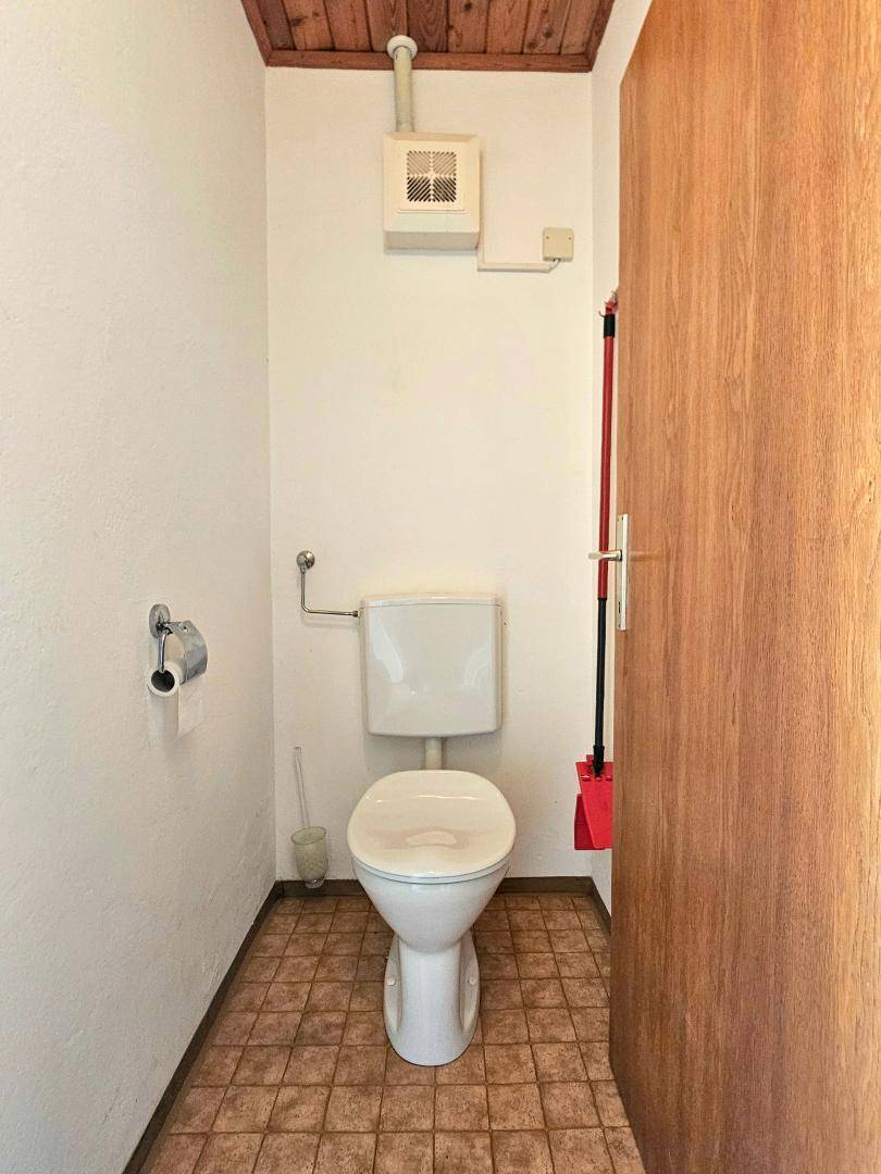 Separates WC mit Fliesenboden und einfacher Ausstattung, ideal für Gäste.