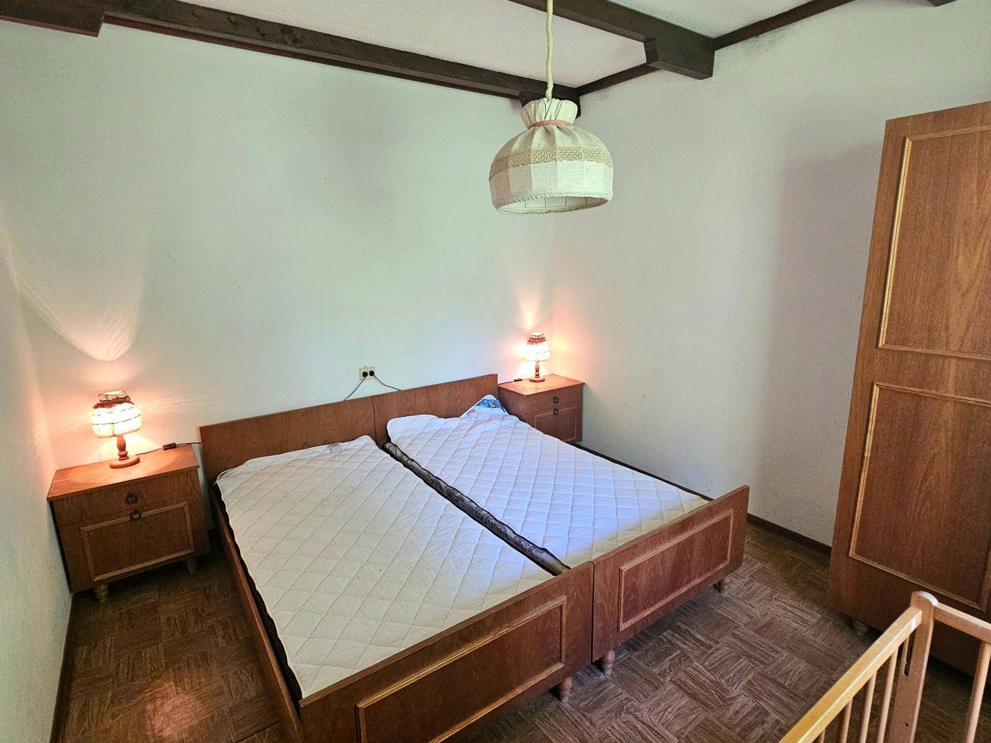 Schlafzimmer mit zwei Einzelbetten, Holzmöbeln und sichtbaren Deckenbalken.