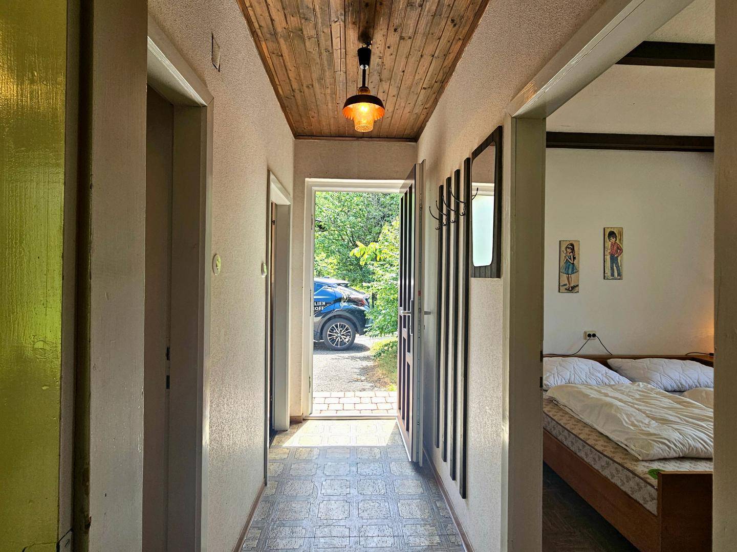 Schmaler Flur mit Holzdecke und Blick auf den Eingangsbereich und das Schlafzimmer.