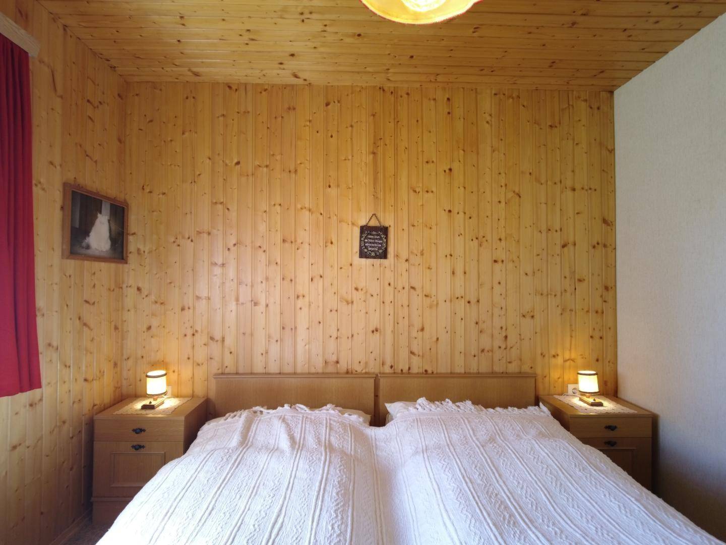 Gemütliches Schlafzimmer mit Holzvertäfelung, Doppelbett und schlichter Einrichtung.