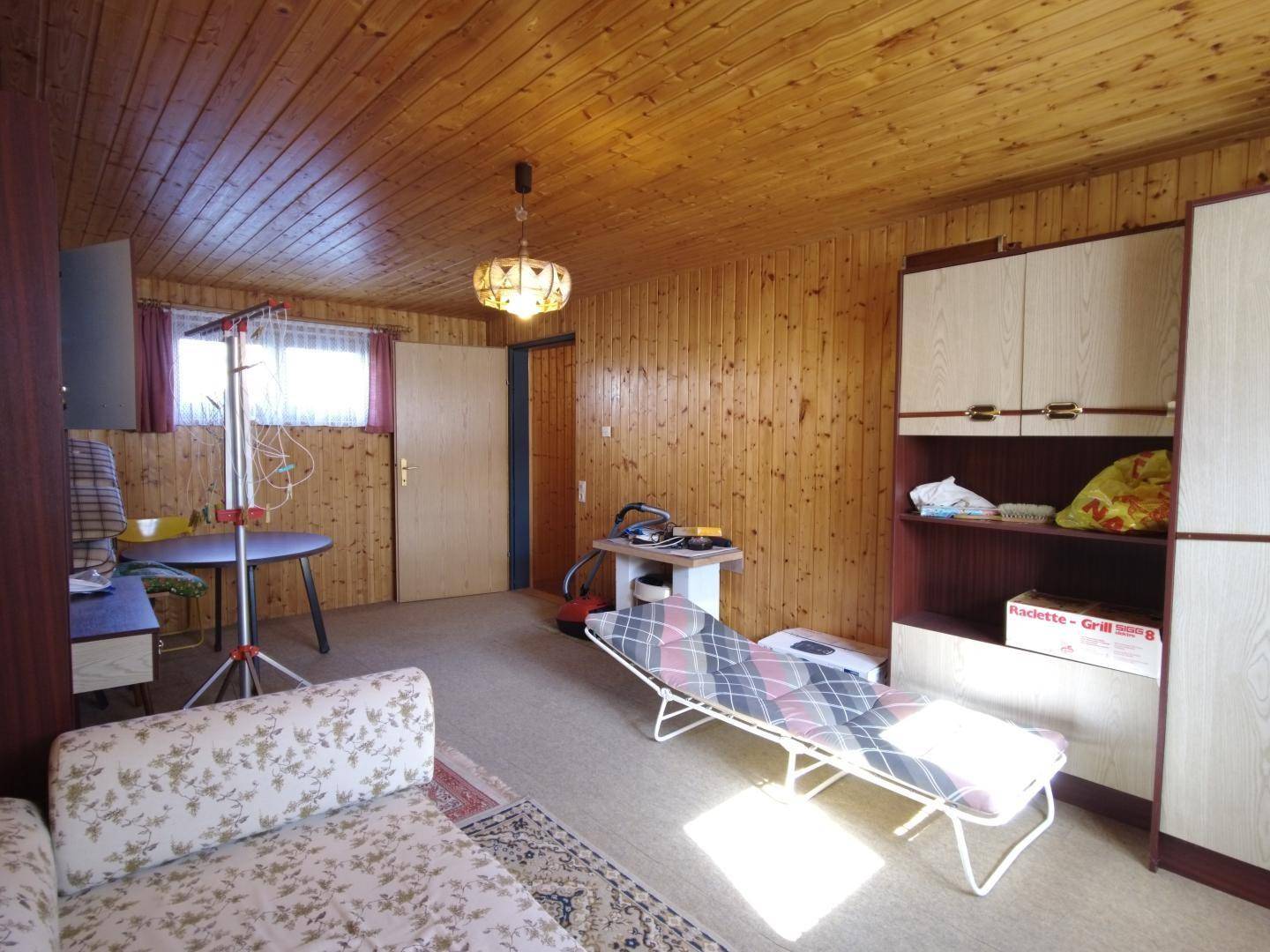 Weiterer Blick in den vielseitigen Raum mit Holzvertäfelung, Tagesbett und Schrankwand, die eine gemütliche Atmosphäre schaffen.