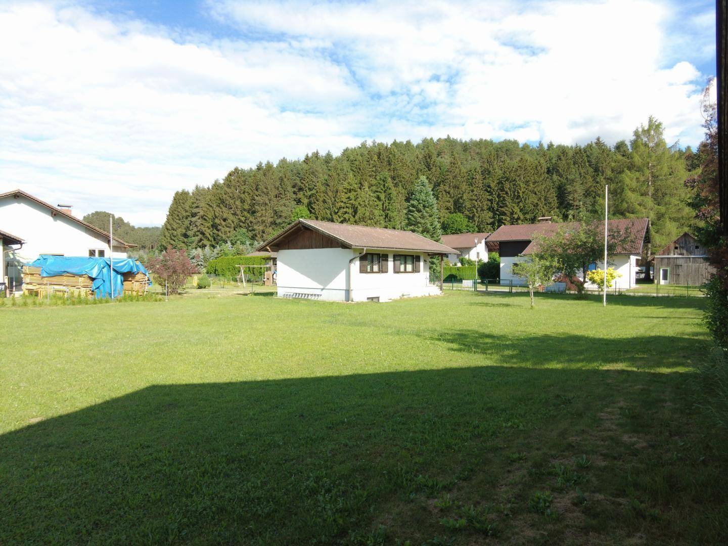 Großer, gepflegter Garten mit Rasenfläche und Blick auf die umliegende Waldlandschaft.