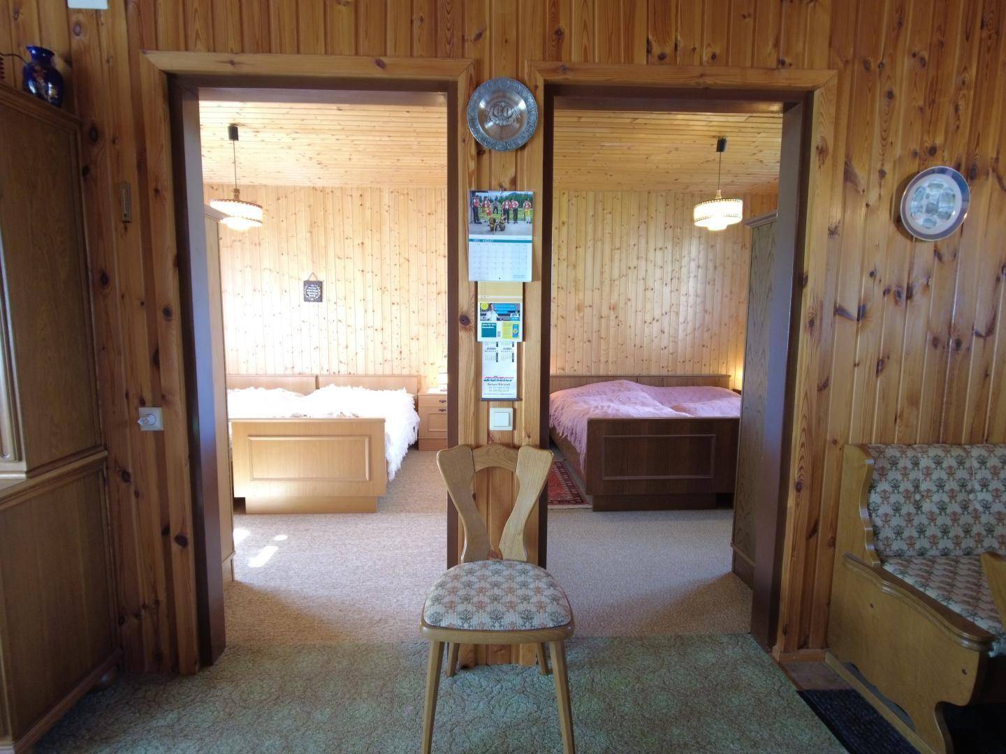 Blick in zwei Schlafzimmer mit Holzvertäfelung und einfacher, traditioneller Einrichtung.