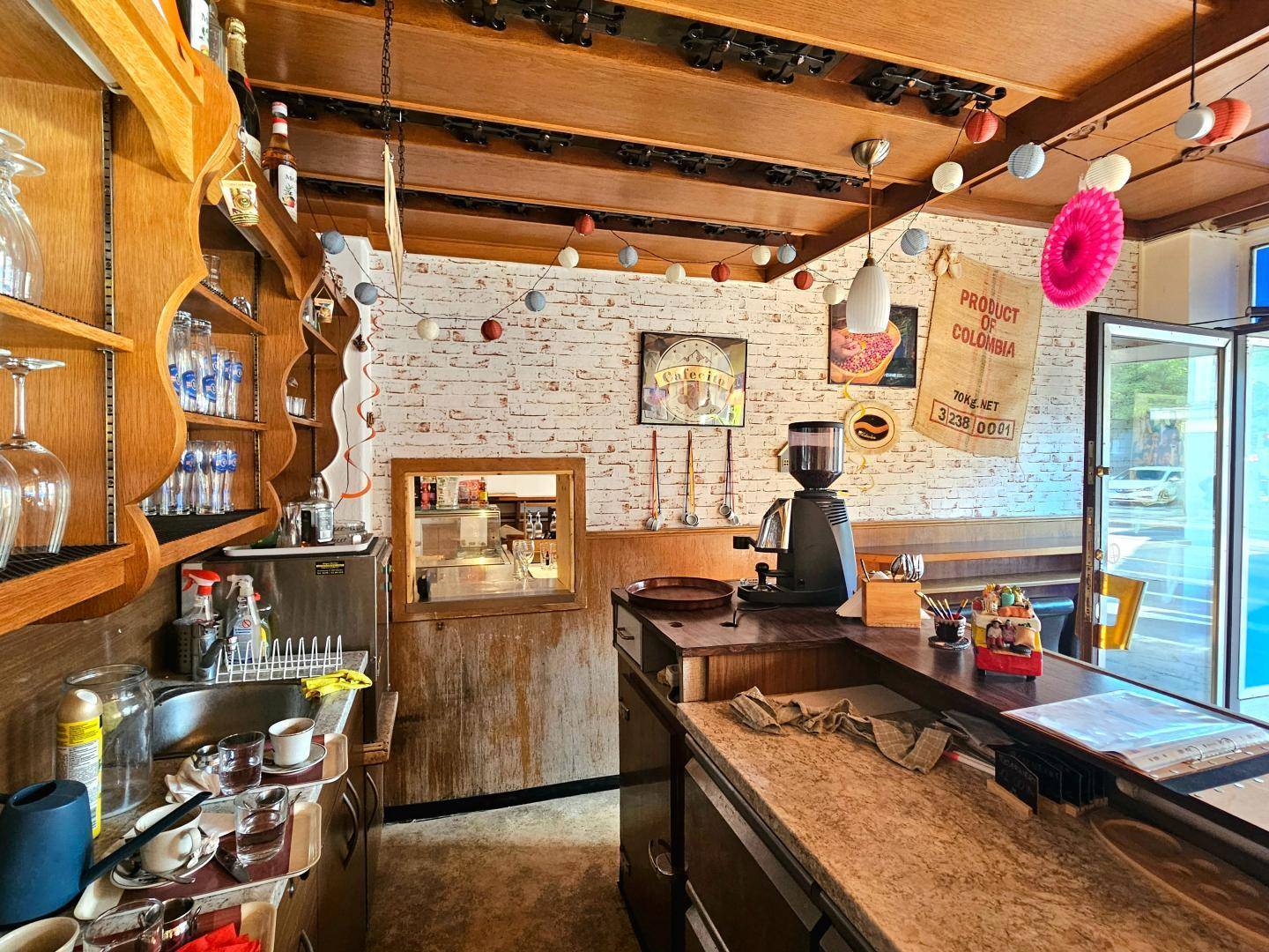 Thekenbereich des Restaurants mit Kaffeemaschine, Regalen und Blick auf den Gastraum.